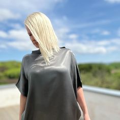 Elevate your wardrobe with our stunning lustrous grey satin top, designed in a loose-fit style. Fold the hem up over your hips or tucked into a pair of pants or a skirt. Whether it's a day at the office, a night out with friends, or a romantic date, this top adds an elegant touch to any occasion. Crafted from a luxurious heavyweight satin, it drapes beautifully, offering effortless sophistication with every movement Proudly made in Izmir Turkey by Kopenhag Studio Good to know The model is 5'6" and wears a small Ecovero from Lenzing is a sustainable vegan silk made from responsibly sourced wood pulp. Handwash inside out or wash inside out on cold Sleek Metallic Tops For Night Out, Sleek Party Tops With Sheen Detail, Sleek Party Tops With Sheen, Chic Satin Tops With Sheen, Sleek Party Top With Sheen, Sleek Sheen Party Top, Sleek Tops With Sheen For Night Out, Chic Gray Evening Tops, Sleek Evening Tops With Sheen