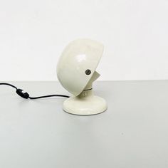 a white lamp sitting on top of a table next to a black cord attached to it