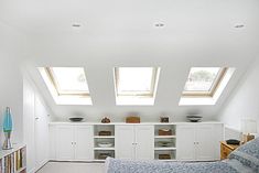 an attic bedroom with two skylights above the bed and bookshelves on the wall