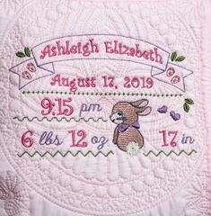 a birth announcement with a pink quilted blanket and embroidered mouse on it's side