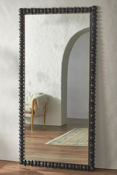 a mirror that is on top of a wooden floor in front of a white wall