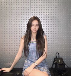 a young woman sitting on top of a black bench next to a handbag and purse