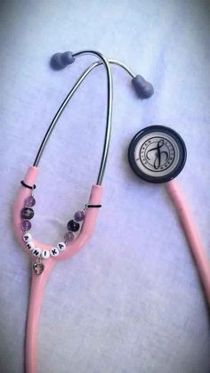 a pink stethoscope laying on top of a bed next to a button