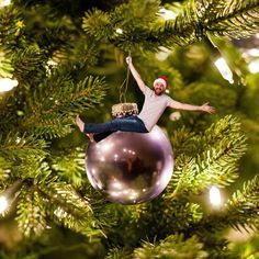 a man is hanging from a christmas tree ornament with his hands in the air