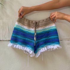 a woman is holding up a crocheted shorts with fringes on the bottom