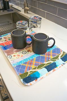 two black mugs sitting on top of a kitchen counter