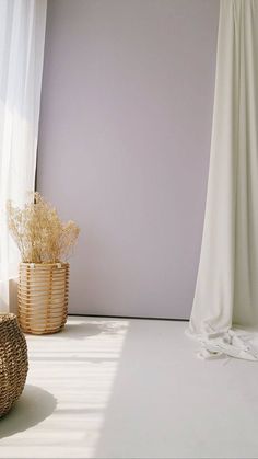 an empty room with a wicker basket next to it and a curtain in the background