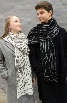 a man and woman standing next to each other wearing scarves on their heads while looking into the distance