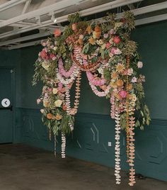 an arrangement of flowers hanging from the ceiling in a room with green walls and doors