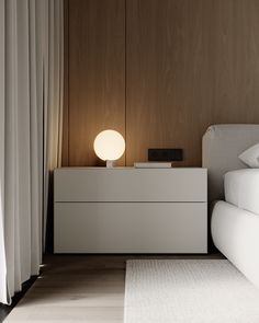 a white bed sitting next to a nightstand with a light on it's side