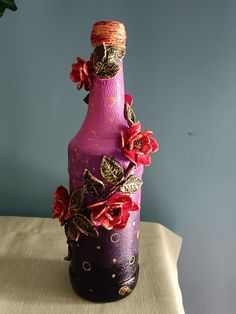 a purple bottle with flowers on it sitting on a table