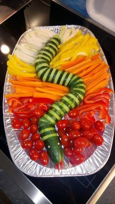 sliced vegetables are arranged in the shape of a caterpillar on a platter