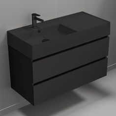 a black bathroom sink sitting on top of a white tiled floor next to a wall mounted faucet