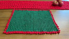 two crocheted placemats sitting on top of a wooden table next to an apple