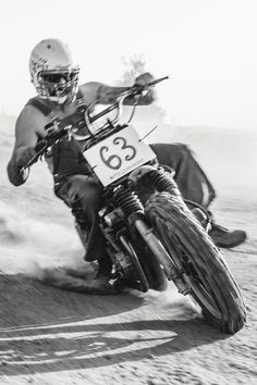 a man riding on the back of a motorcycle down a dirt road