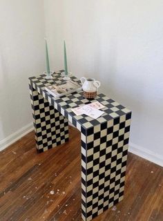 two black and white checkered tables with candles on each side, in front of a wall