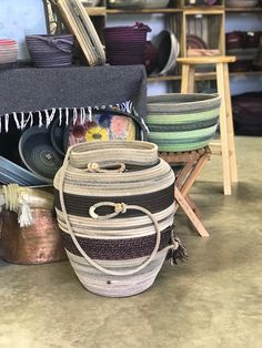 the basket is sitting on the floor next to many other baskets and rugs in front of it