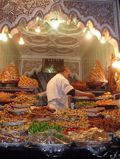 a man is standing in front of many trays of food that are on display