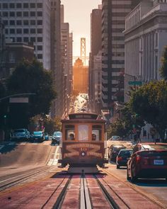 a trolley car is traveling down the tracks in front of some tall buildings and cars