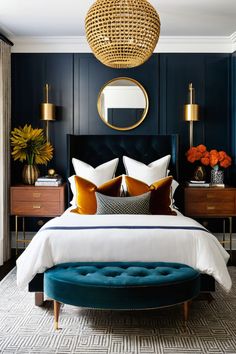 a bedroom with dark blue walls and white bedding, gold mirror above the headboard