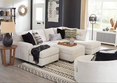 a living room filled with white furniture and lots of pillows on top of it's couches