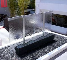 a water fountain in front of a building with plants growing out of it's sides