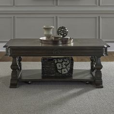 a coffee table with two vases on it and a clock above the top, in front of a gray paneled wall