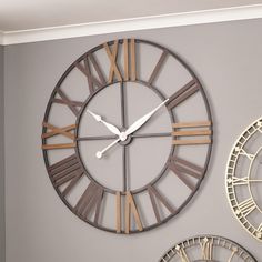 a large clock on the wall next to two smaller clocks with roman numerals