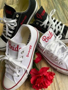 three pairs of shoes with bride and groom's names on them next to a red flower