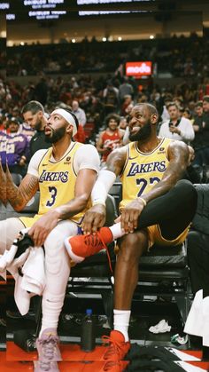 two lakers players sitting on the bench during a game