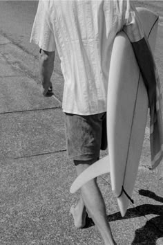 a man walking down the street with his surfboard