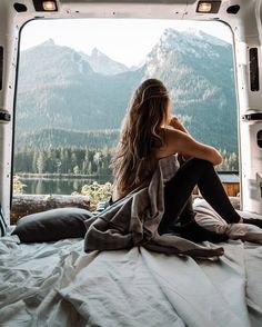 a woman sitting on top of a bed next to a window in the back of a truck