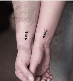 two people holding hands with matching tattoos on their arms and wrist, both wearing crowns