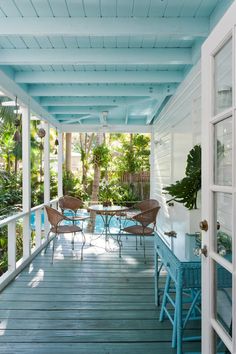 an outdoor covered porch with blue chairs and tables