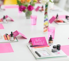 the table is set up with pink and white flowers in vases, pens, and markers