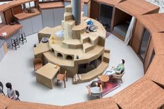 an aerial view of people sitting in chairs around a circular table with stairs on it