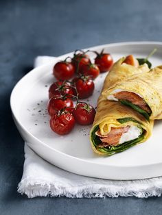 a white plate topped with a wrap and cherry tomatoes