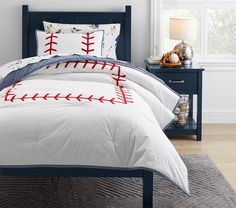 a baseball themed comforter and pillow set in a child's bedroom with blue nightstands