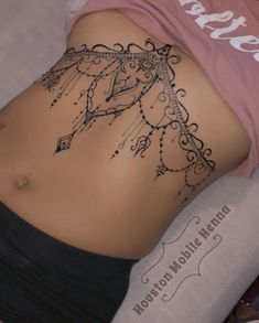 a woman laying on top of a bed with her stomach covered in black and white tattoos