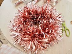 tinsel wrapped wreath sitting on top of a table next to scissors and other crafting supplies