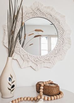 a white vase sitting on top of a table next to a mirror and beaded necklace