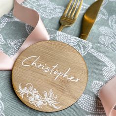 a personalized wooden place setting on a table with pink ribbon, fork and knife