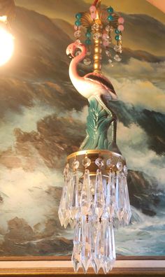 a chandelier hanging from the ceiling in front of a painting with a flamingo on it