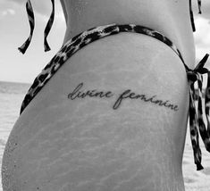 a woman's lower back tattoo with the words divine person written in cursive font