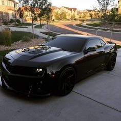 a black sports car parked in front of a house