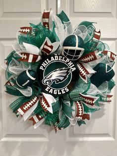 the wreath is decorated with green and white mesh, footballs, and philadelphia eagles