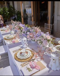 the table is set with pink and white flowers in vases, plates, and napkins