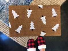 someone is standing in front of a door mat with christmas trees on it