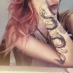 a woman with red hair and tattoos on her arm