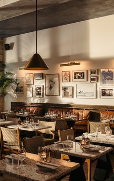 an empty restaurant with tables and chairs in front of pictures on the wall above them